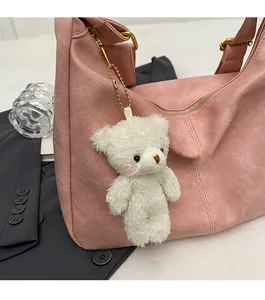 Close-up of white plush bear keychain on a pink faux leather tote bag with lychee texture