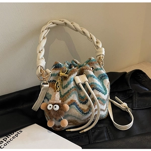 Detalle de bolso saco de punto con ondas azules, asa trenzada y colgante de monstruo suave