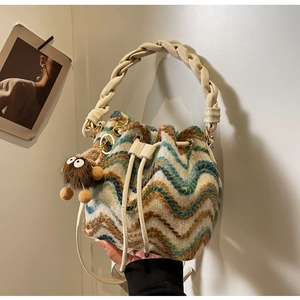 Detalle del bolso de punto tipo cubo con diseño de chevrón y asa de cuero trenzado