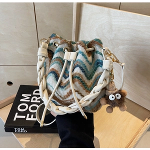 Detalle de bolso cubo de punto con asa de cuero trenzado y colgante de peluche suave