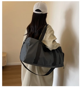 Detail of grey waterproof nylon travel bag showing spacious side zipper pockets and straps