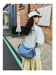Model showcasing a large washed denim crossbody bag in a retro casual street scene style