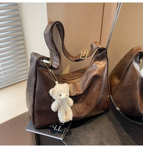 Detail of dark brown retro tote bag with adjustable strap and cute plush bear charm