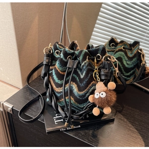 Detalle de bolso cubo de punto con diseño zigzag y colgante de monstruo de peluche