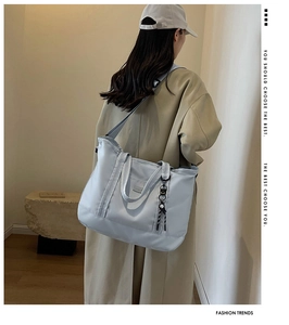 Large capacity light blue travel bag with adjustable strap and decorative side charm