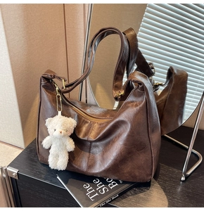 Close-up of vintage brown PU leather tote bag with a white plush bear charm on its side