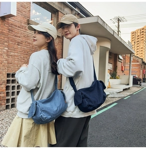 Detail of high-capacity denim crossbody bags in light and dark blue on street models
