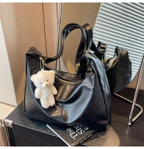 Detailed back view of a black retro oil-waxed tote bag reflected in a mirror with plush bear charm