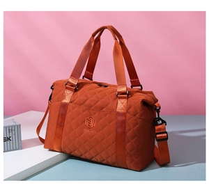 Detailed close-up of orange quilted Oxford travel bag with adjustable strap and brand logo