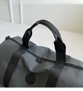 Detail of gray travel duffel bag showing durable nylon fabric and reinforced woven handles