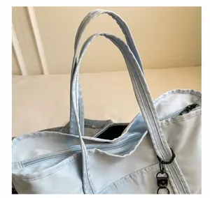 Close-up of comfortable dual handles and metal zipper detail on light blue travel bag