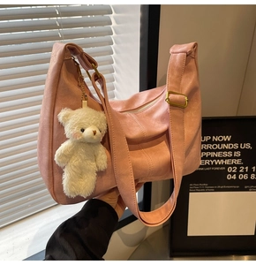 Detail view of pink PU leather tote bag with a plush bear charm and golden hardware