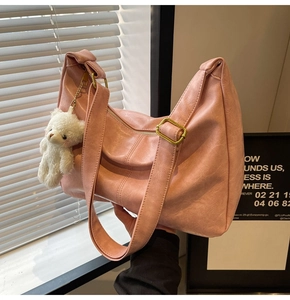 Detailed view of pink hobo tote bag with gold zipper and white plush bear charm