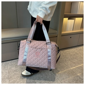 Detailed shot of pink quilted nylon travel bag featuring logo embroidery and wide handles