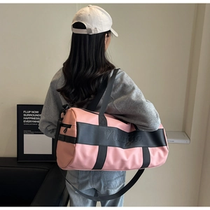 Macro view of pink and black nylon travel bag featuring embossed brand logo detail