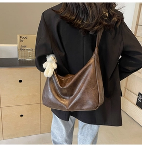Detail of deep brown retro hobo tote bag with textured faux leather and bear charm