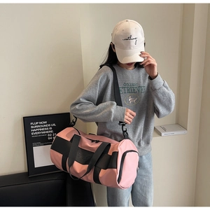 Detailed view of pink nylon travel bag with side zipper pocket and black shoulder strap