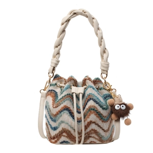 Bolso saco de punto multicolor con colgante de peluche y asa trenzada crema sobre fondo blanco