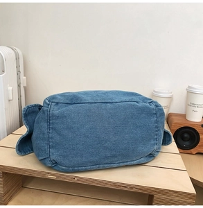 Close-up of durable blue denim bag material and stitching on a wooden shelf