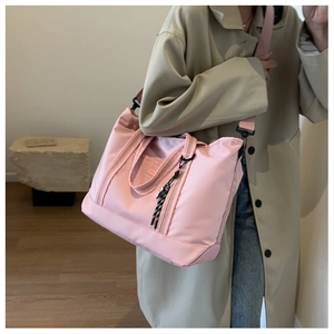 Pink waterproof nylon large travel tote bag with shoulder strap worn by a female model