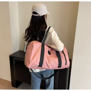 Pink waterproof nylon travel bag with black straps shown from back during usage