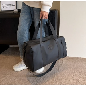Close-up of black nylon travel bag featuring a round logo and adjustable shoulder strap