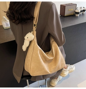 Rear view of a model wearing the beige faux leather tote bag with a plush bear charm