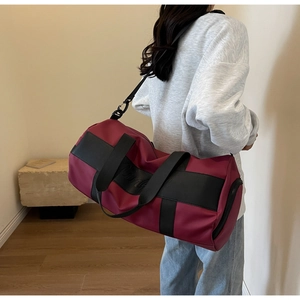 Detail of burgundy nylon travel bag with black straps in minimalist interior setting