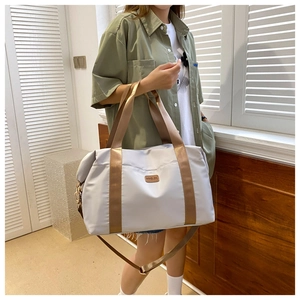 Détail du sac de voyage gris en Oxford avec poignées bronze et bandoulière réglable