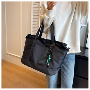 Close-up of a black large capacity travel tote bag with stripe cord charm decoration