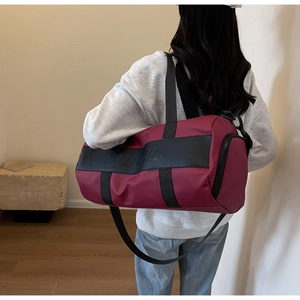Detail of burgundy nylon travel bag showing crossbody strap and side zipper finish