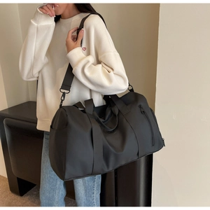 Detail of black nylon travel bag featuring side zipper pocket and sturdy carry handles