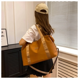 Détail d'un sac de voyage jaune gingembre avec poignées et bandoulière réglable amovible