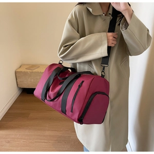Detail view of burgundy nylon travel bag with shoe compartment and adjustable shoulder strap