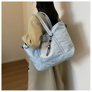 Detailed view of light blue nylon tote bag with decorative lanyard on female model