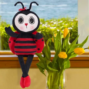 Detail of cute ladybug plush with red bow sitting by yellow tulips on a bright window sill