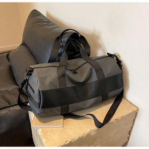 Detail of grey nylon travel bag with black leather straps on a stone pedestal