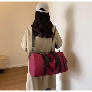 Back view of model carrying large fuchsia nylon travel bag with adjustable strap