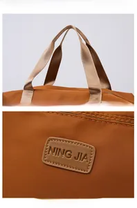 Détail de la texture en nylon et du logo en cuir sur le sac de voyage marron en oxford