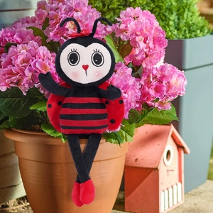 Detail of ladybug plush toy with long legs and wings sitting on pink hydrangea plant
