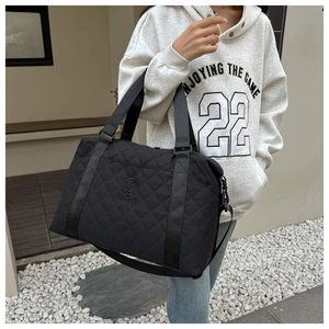 Close-up of black quilted oxford bag with adjustable shoulder strap and metal hooks