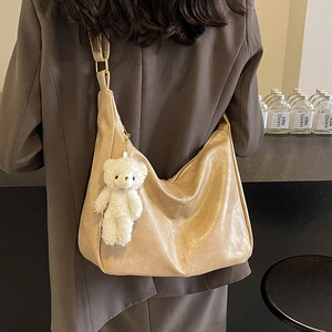 Oatmeal beige large tote bag with plush bear charm worn over the shoulder for daily commute