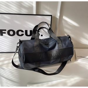 Detailed close-up of navy nylon duffle bag featuring black handles and logo branding