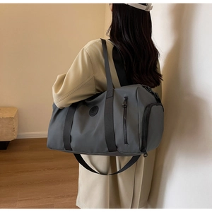 Rear view of a model carrying a large grey nylon travel bag with wide black straps