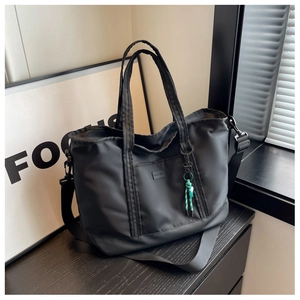 Detail of black waterproof nylon travel tote bag with shoulder strap and rope charm