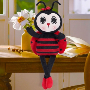 Cute ladybug plush doll with long legs and red bow sitting on a desk as home decoration