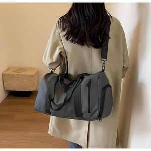 Detail view of large charcoal nylon travel bag featuring reinforced handles and side shoe pocket
