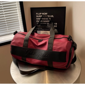 Close-up of waterproof burgundy nylon travel bag showing brand logo and handle detail