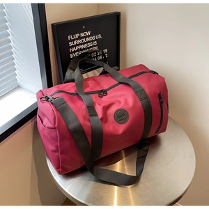 Macro view of large burgundy nylon travel bag with durable straps on a metal table