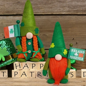 Close-up of St. Patrick's Day gnomes with clover hats and Ireland flags on wood background